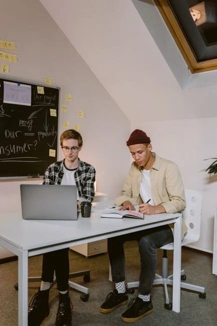 A man uses a laptop indoors to study a stock market trend graph displayed on the screen.
